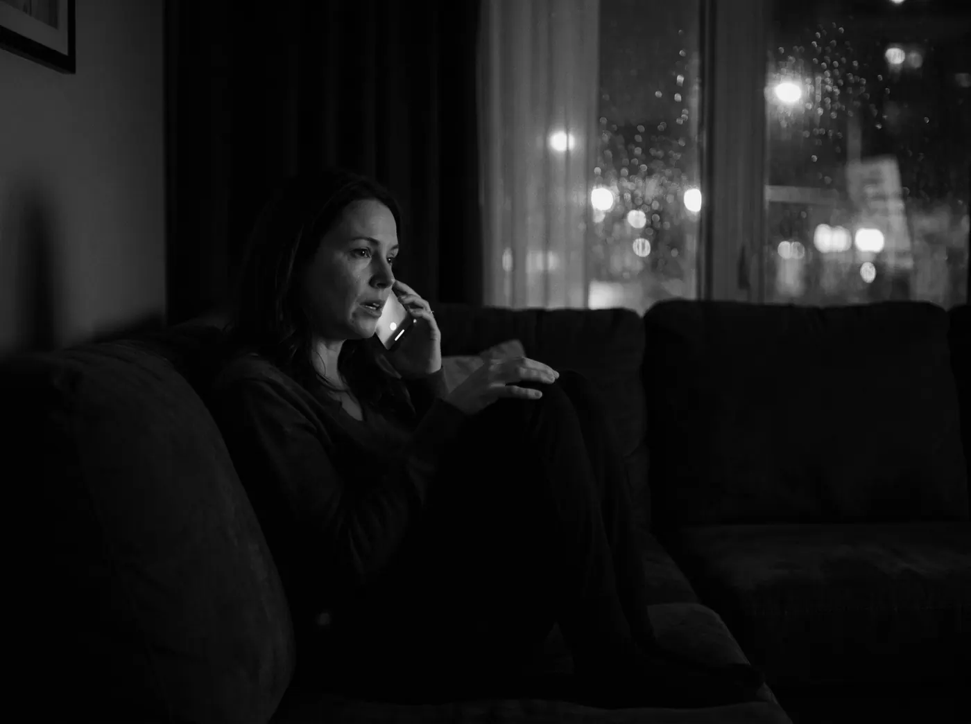 A woman at home at night asking her phone a question