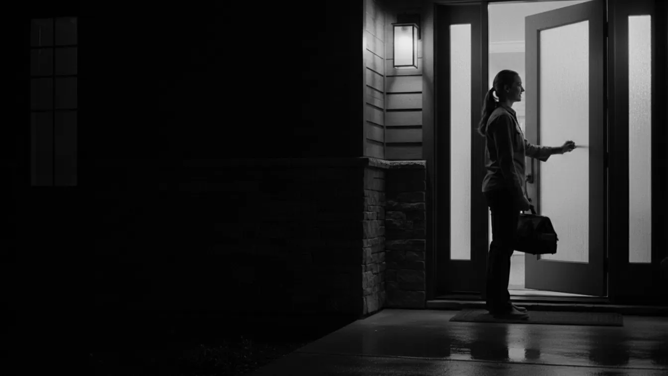 A technician arriving at a front door at dusk